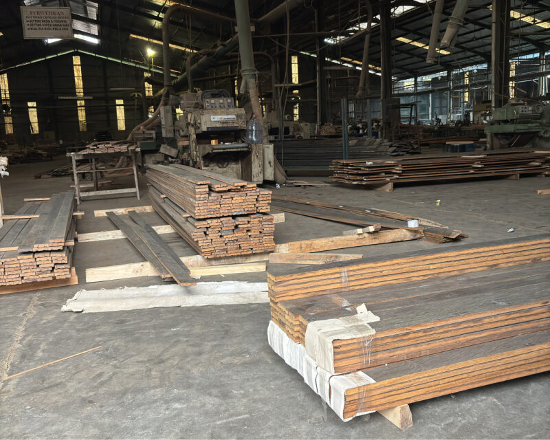Stacks of reclaimed hardwood boards and beams on the floor of a timber processing factory