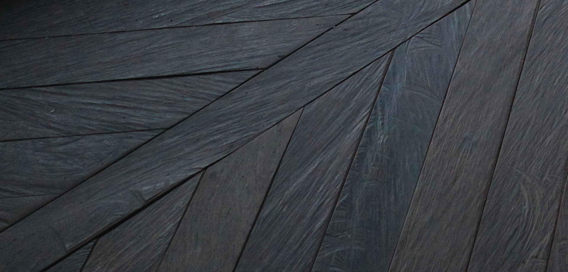 Close-up of weathered dark grey ironwood deck boards laid in a fanned, angled pattern