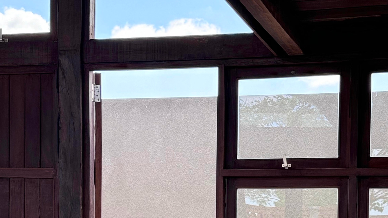 Dark solid timber-framed windows and clerestory glazing set into a hardwood-clad wall under blue sky