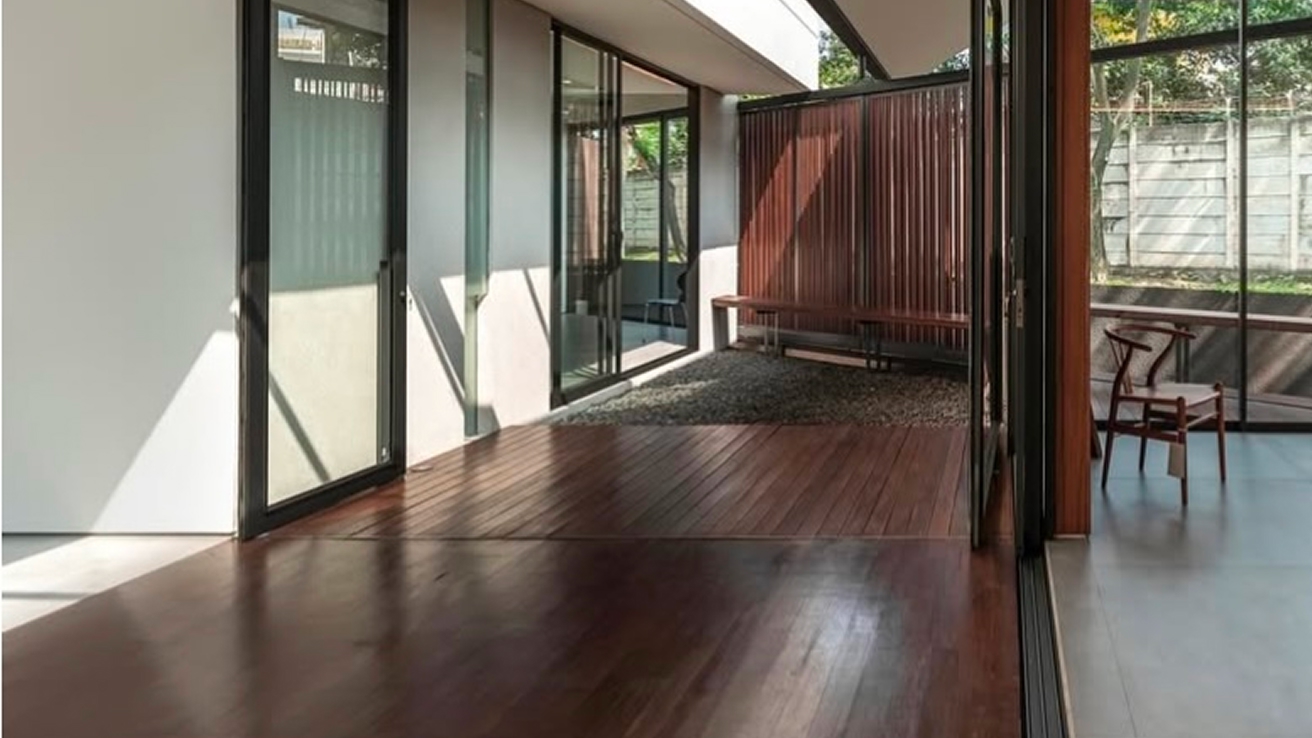 Polished reddish-brown hardwood flooring on an open patio with sliding glass doors and a timber bench