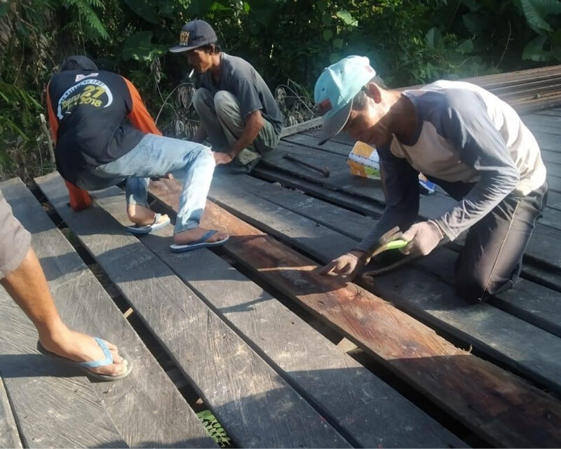 Workers sanding and finishing dark reclaimed hardwood decking boards outdoors