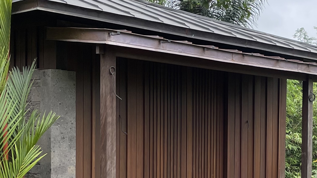 Dark-stained vertical timber cladding on a building exterior beside a stone wall